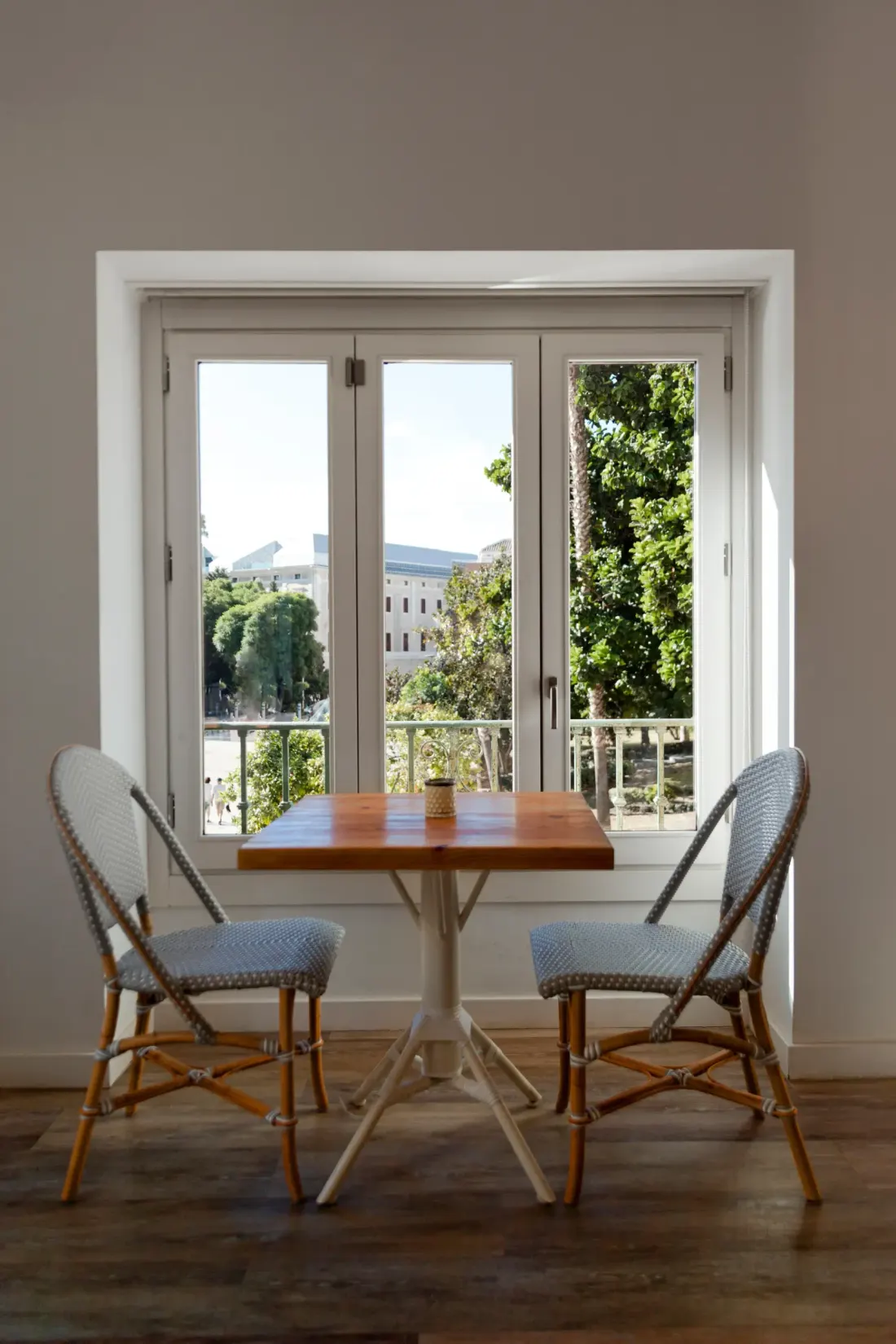 Ventana balconera blanca abierta junto a una mesa de comedor